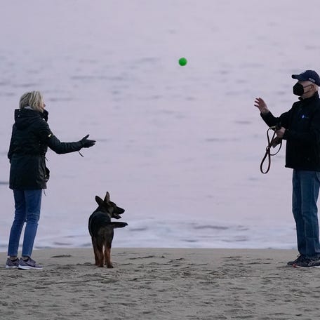 First lady Jill Biden tosses a ball to President Joe Biden as they take their dog Commander for a walk in Rehoboth Beach, Del., Tuesday, Dec. 28, 2021. 