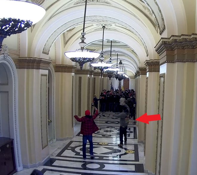 This image of two men waving to a crowd in the Jan. 6 U.S. Capitol riot was included in a sentencing memo a prosecutor filed about First Coast resident Jeffrey Register. The memo identifies Register as  the man marked by an arrow, standing in a hallway leading to the House Speaker's Lobby.