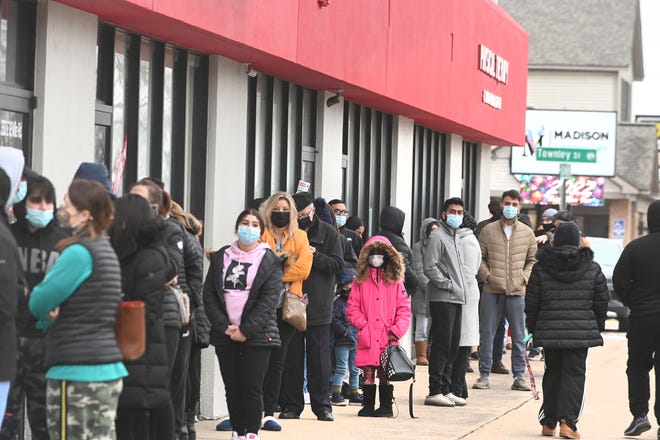 A line of people wait for COVID-19 tests at the Get Well Urgent Care in Madison Heights on Thursday, Dec. 30, 2021.
