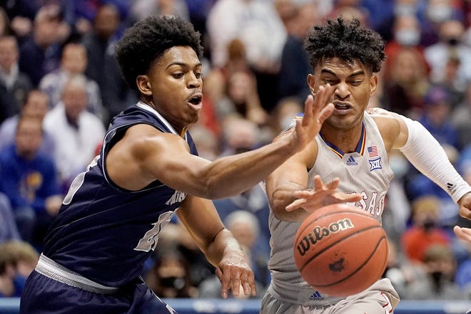 Nevada guard Grant Sherfield, left, and Kansas' Remy Martin chase a loose ball during the first half of an NCAA college basketball game Wednesday, Dec. 29, 2021, in Lawrence, Kan. (AP Photo/Charlie Riedel)