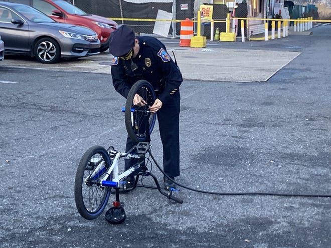 Wilmington police help to fill the air in a child's bike tire after their investigation closes off the BP gas station Dec. 29, 2021.
