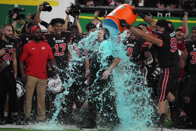 Utah head coach Kyle Whittingham is doused with a Gatorade cooler by defensive tackle Devin Kaufusi (90) during the 2021 Pac-12 championship game.
