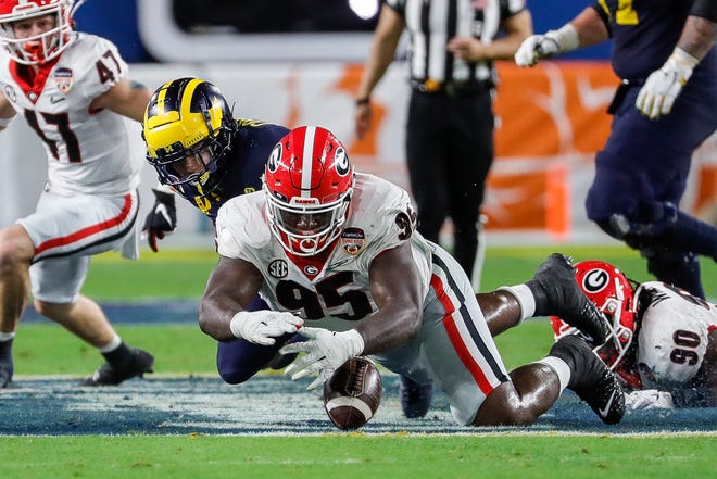 Georgia defensive lineman Devonte Wyatt (95) recovers a fumble by Michigan running back Blake Corum (2) during the second half of the Orange Bowl at Hard Rock Stadium in Miami Gardens, Florida, on Friday, Dec. 31, 2021.