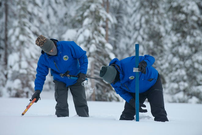 Anthony Burdock, left, and Sean de Guzman, chief of snow surveys for the California Department of Water Resources, check the depth of the snow pack during the first snow survey of the season at Phillips Station near Echo Summit, Calif., Thursday, Dec. 30, 2021. The survey found the snowpack at 78.5 inches deep with a water content of 20 inches. Statewide, the snow holds 160% of the water it normally does this time of year. (AP Photo/Randall Benton)