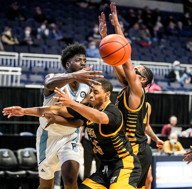 URI's Makhi Mitchell passes around American International defenders in the second half of Sunday's game in Kingston.