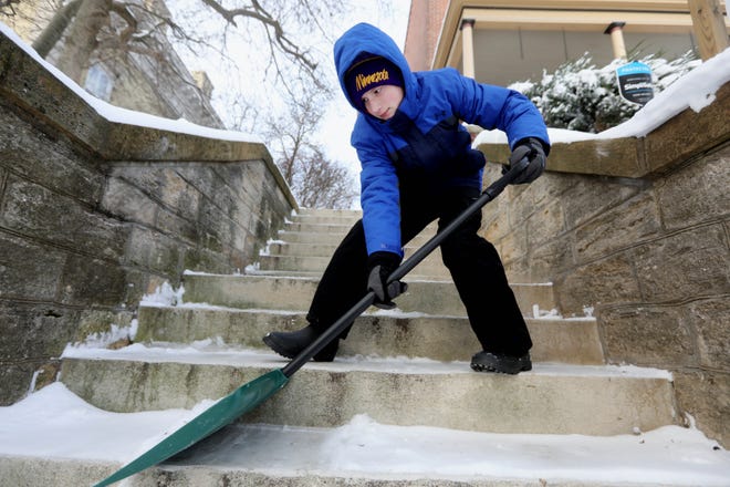 Carter Shinn, 13, shovels the snow from the steps leading to his house while his father Matt Shinn uses a snowblower to remove snow from the sidewalk along the block in front of their home while cleaning up following Saturday's snowfall which covered the area with nearly 8 inches of snow Sunday Jan. 2, 2022 in Burlington.  