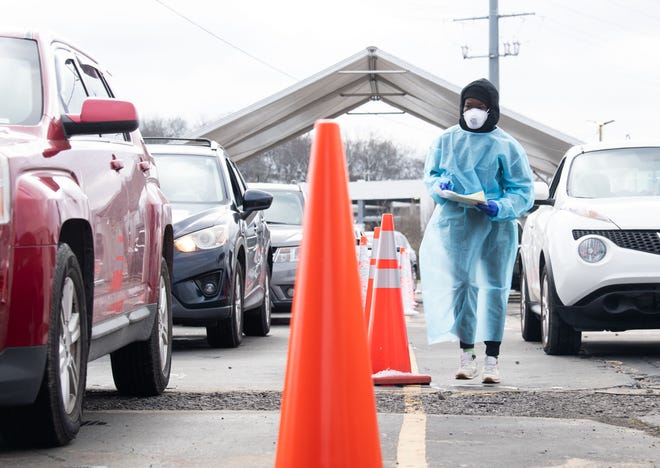 A worker collects information from people while sitting in their cars at the 28th Avenue North COVID-19 test and vaccination site on January 3rd.