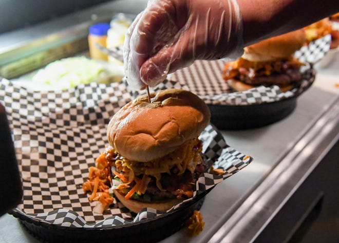 Tony Keupp grills places a toothpick into a freshly made GochuJANGÕS All Here Burger at JL Beers as part of the downtown Burger Battle on Saturday, January 1, 2022 in Sioux Falls.