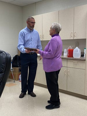 Newcomerstown Supterintendent Jason Peoples, left, congratulated Arlene Mayhew at her final meeting as a member of the Newcomerstown Board of Education.