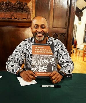 The Rev. Earle Fisher holds a copy of his new book, 'The Reverend Albert Cleage Jr. and the Black Prophetic Tradition.'