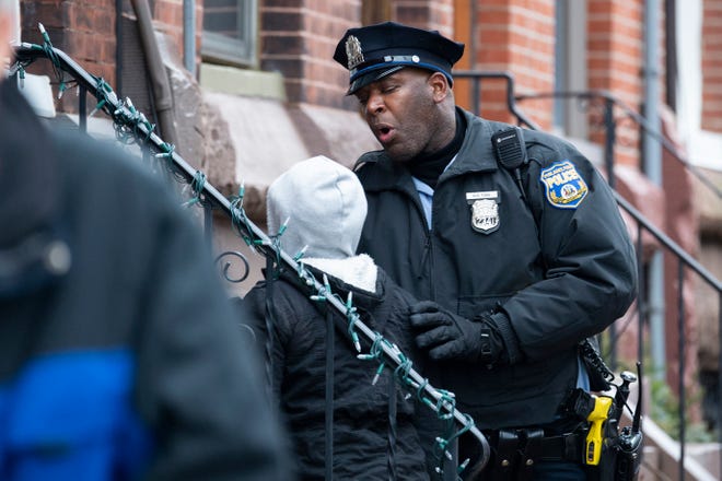 A police officer holds back a woman attempting to get on the scene of a fatal fire on the 800 block of N. 23rd Street in Philadelphia, Pa. on Wednesday, Jan. 5, 2022.