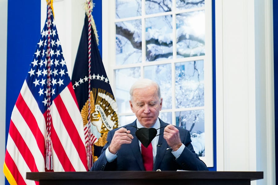 President Joe Biden removes his face mask as he arrives to meet with the White House COVID-19 Response Team on the latest developments related to the Omicron variant in the South Court Auditorium in the Eisenhower Executive Office Building on the White House Campus in Washington, Tuesday, Jan. 4, 2022.