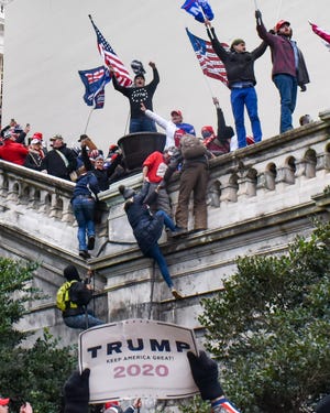 Supporters of then-President Donald Trump scale a wall of the U.S. Capitol's West Front during the insurrection in Washington on Wednesday, Jan. 6, 2021. Rioters breached the Capitol building after gathering for a rally opposing the 2020 presidential election results.