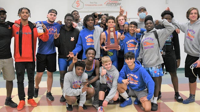 Palm Beach Gardens' wrestlers pose with their victory trophy following their finals win over Jupiter in Wednesday evening's 3A District 11 dual tournament.
