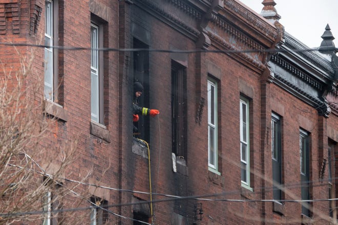 A firefighter pulls a snake up at the scene of a deadly 800-block fire on N. 23rd Street in Philadelphia, Pa. Wednesday, January 5, 2022.