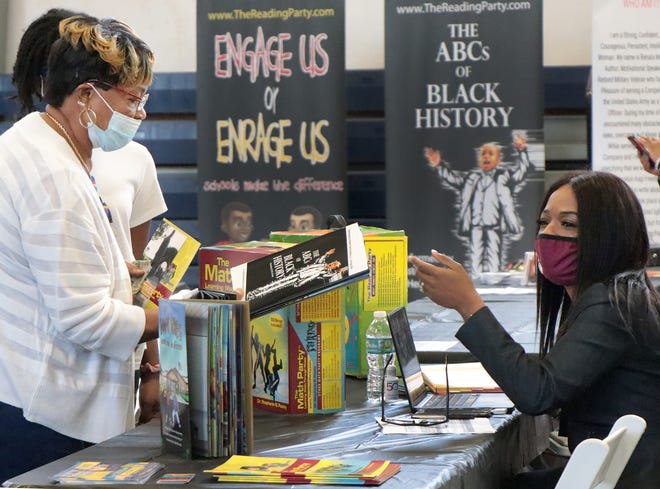 Author Stephanie Pasley-Henry, at right, hands a copy of her book "The ABC's of Black History" during the 11th annual Daytona Beach F.R.E.S.H. Book Festival held at the Midtown Cultural & Educational Center in Daytona Beach.