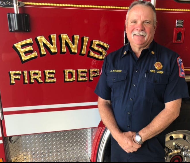 Retiring Ennis Fire Chief Jeff Aycock stands alongside one of his department's fire vehicles. Aycock is retiring after 36 years of service.