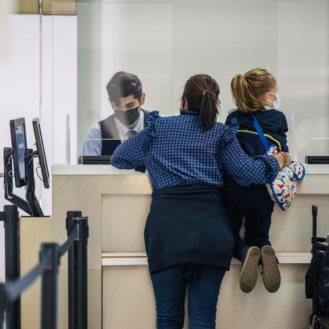 A woman and her child speak with an airline attend