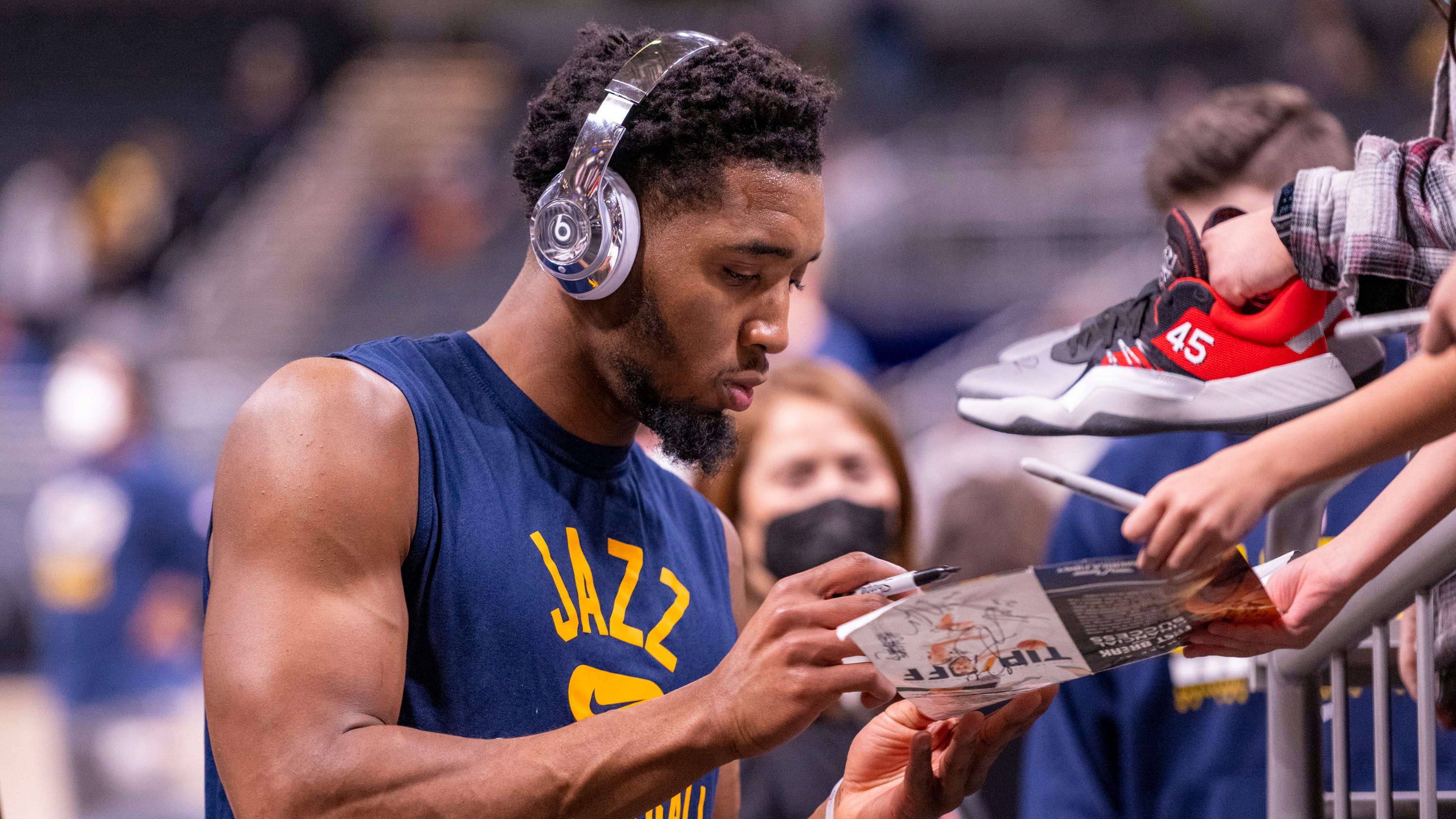 Utah Jazz guard Donovan Mitchell (45) gives an autograph for a fan as he leaves the court after warming up before an NBA basketball game against the Indiana Pacers in Indianapolis, Saturday, Jan. 8, 2022. (AP Photo/Doug McSchooler).
