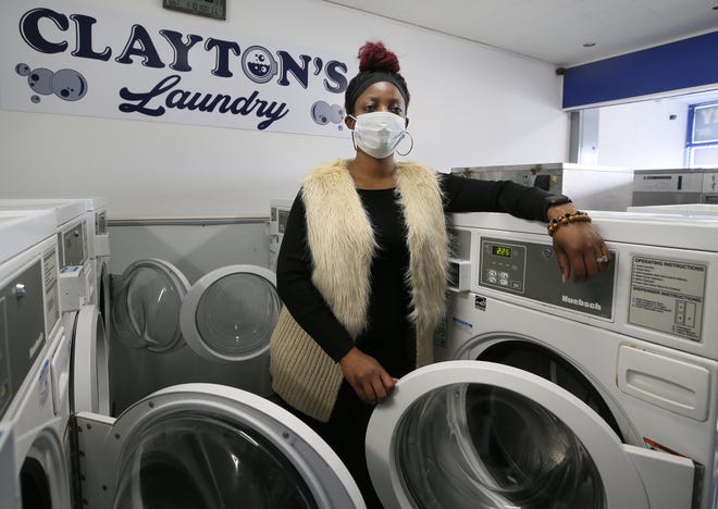 Loretta Clayton stands between a row of front-loading washing machines in her Cuyahoga Falls laundry.