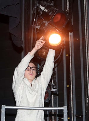 Eighth grader Wittman Sullivan adjusts a light's angle from a lift above the stage at Weathervane Playhouse on Sunday.