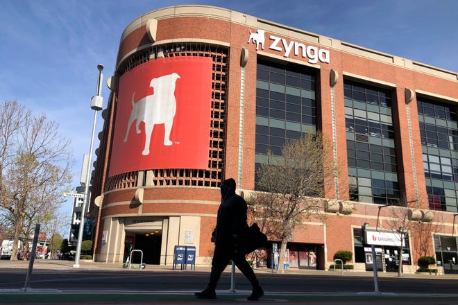 A pedestrian walks in front of a sign at Zynga in San Francisco on March 16, 2021.
