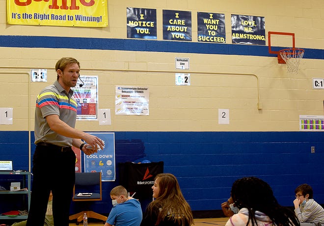 Ryan Armstrong, a physical education teacher at Parkade Elementary School, talks to his students below a sign Armstrong calls his mantra on Tuesday during one of his PE classes. Armstrong has been named elementary physical education teacher of the year for the central district that comprises nine states.