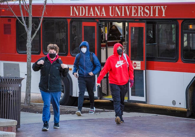 People wearing masks Tuesday get off an Indiana University campus bus along Indiana Avenue.