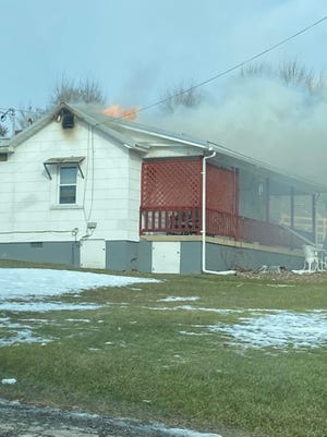 Smoke and flames pour from the roof of a Northwestern Turnpike home that burned Monday afternoon.