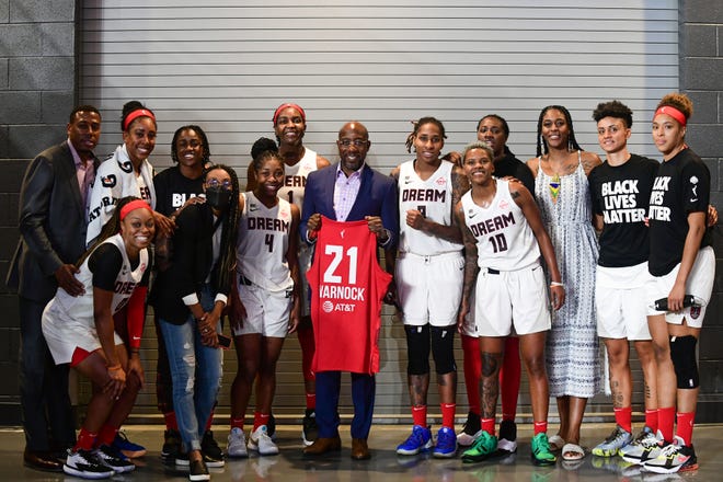 Reverend Raphael Warnock poses with his Atlanta Dream jersey with the team after the game against the Phoenix Mercury on August 21, 2021 at Gateway Center Arena in College Park, Georgia.