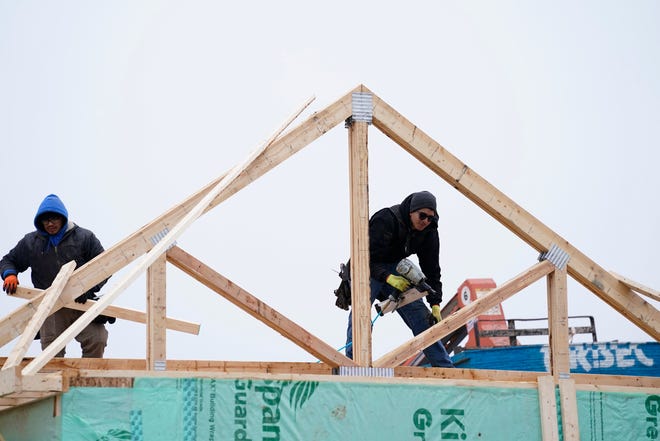 Single-family houses are under construction at Legacy Estates, a new Lombardo Homes development in Macomb, on Jan. 13, 2022. Workers install a roof truss on one of the new houses.