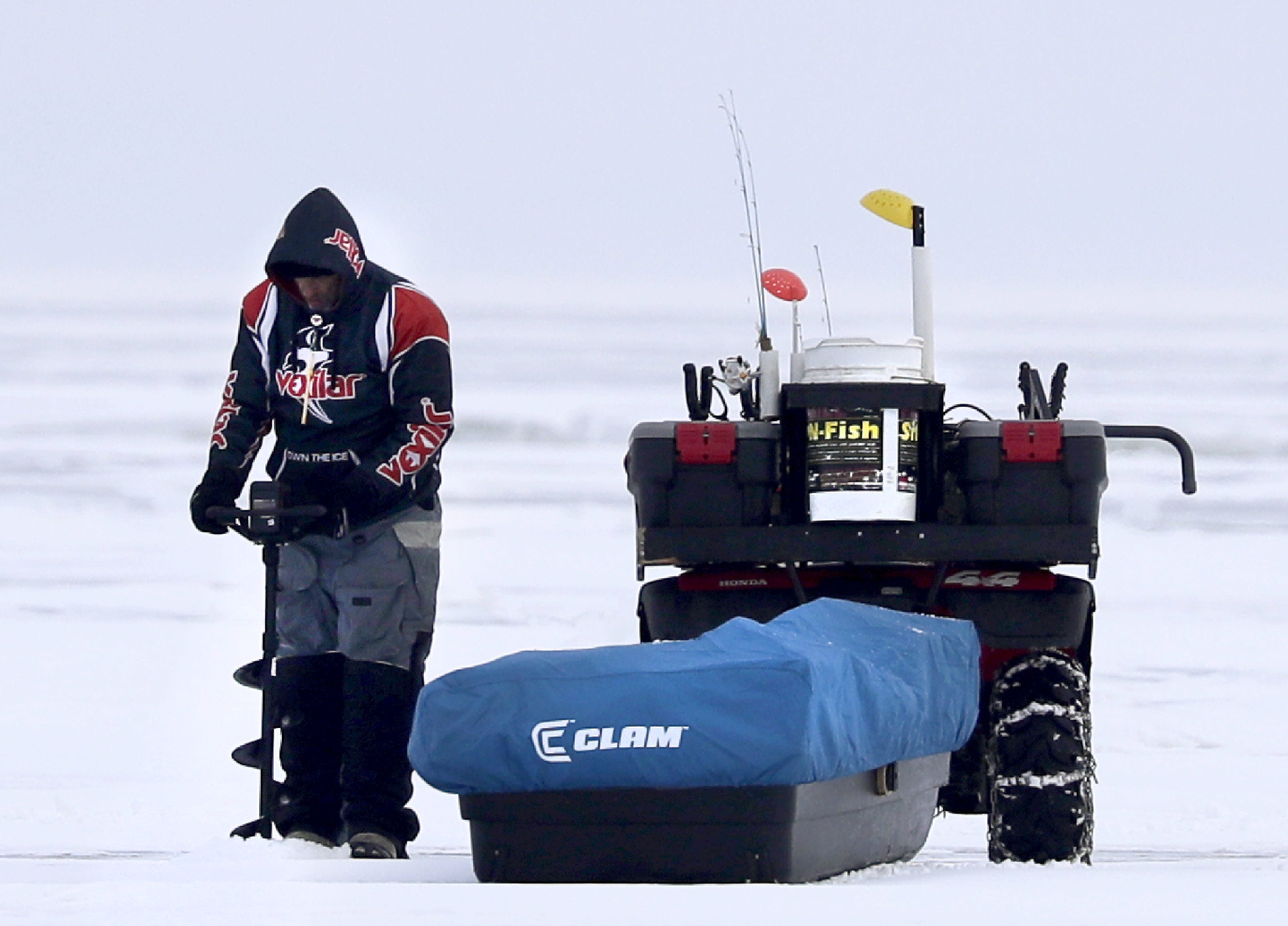 A man drills a hole in the ice while fishing on Lake Winnebago on Thursday in Oshkosh.