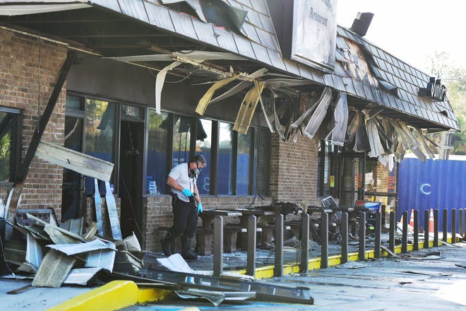 A police detective examines the damage from a fire at Junior's Seafood Restaurant & Grill and adjacent Junior's Famous Sandwiches. Owned by the same family, who want to rebuild, both North Jacksonville restaurants were gutted by fire Thursday after being in business nearly 45 years.