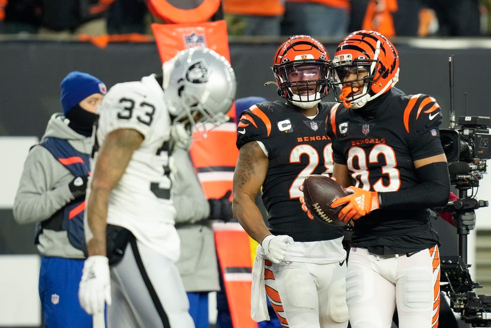 Cincinnati Bengals' Tyler Boyd (83) and Joe Mixon (28) react to a touchdown by Boyd in front of Las Vegas Raiders' Roderic Teamer (33) during the first half of an NFL wild-card playoff football game, Saturday, Jan. 15, 2022, in Cincinnati.