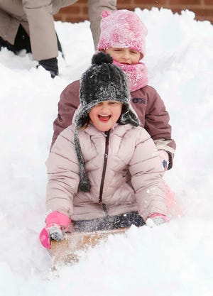 Sisters Kaitlyn Bell, front, and Lily Bell take their toboggan on its first run of the season down the hill in front of Firestone Park Elementary School Monday in Akron.