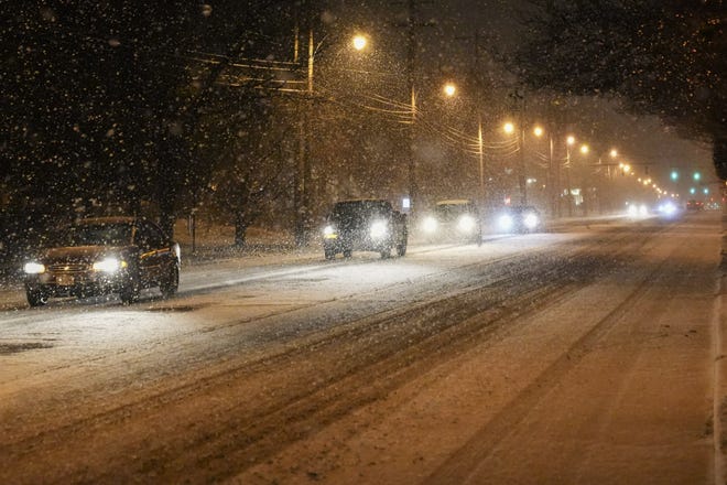 Cars drive along High Street as snow falls in Clintonville on Sunday.