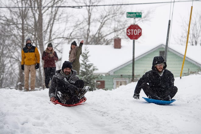 Michael Figueroa, left, and Christopher Worrell sled down an unplowed Wamboldt Ave in West Asheville January 16, 2022.