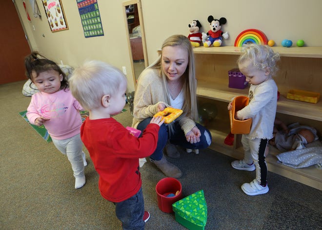 Director Jessica Carpenter hands toys to Graham Griess, front, with Nevaeh Caro, left, and Eilee Wray, right, in the Waddler 1 Room at Our Redeemer Early Learning Center. 