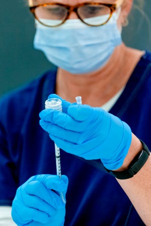 A nurse fills syringes with the COVID-19 vaccine for distribution.