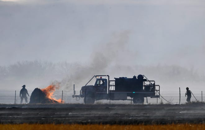 The crew of an Abilene Fire Department brush truck prepares to put out a hay bale that caught fire during Thursday's grass fire near State Highway 351 north of Abilene. While a handful of homes were threatened, the fire was quickly contained by AFD and responders from several volunteer fire departments.