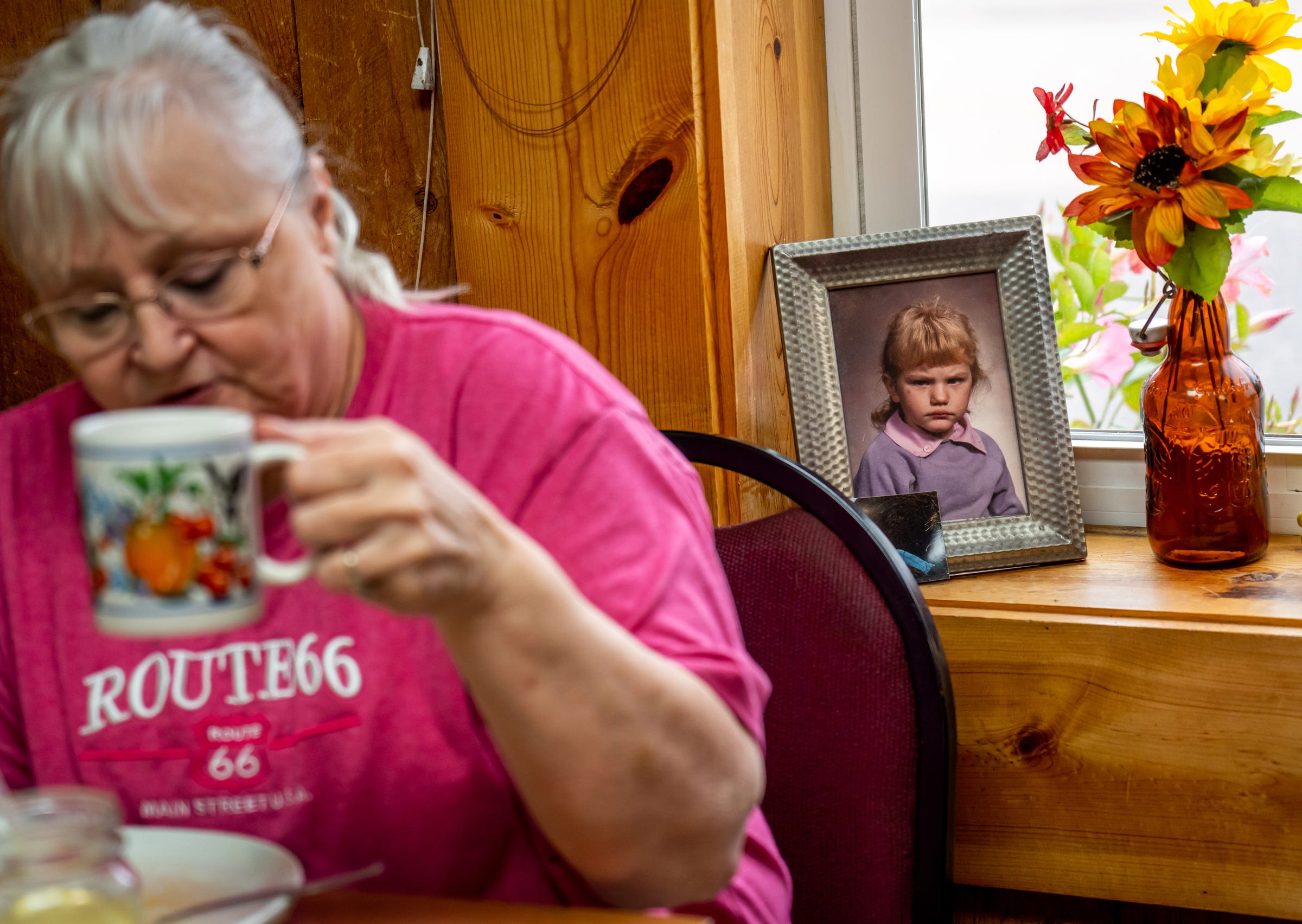 Jan Wehmeyer, of Gwinn, enjoys her breakfast next to an elementary school photo of Shannon's Home Cooking owner Shannon Greathouse when she was a troubled little girl, on display inside the family style restaurant in Gwinn on Wednesday, Oct. 20, 2021.
