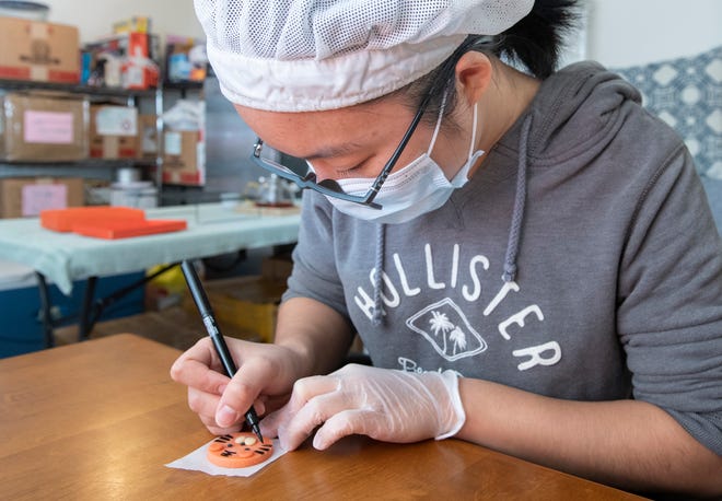 Liang Xu, owner of The Pretty Bear's Bakery, hand paints details on tiger cookies in Pensacola on Thursday. Xu will be selling these cookies and other treats for the Lunar New Year at Gallery Night and at the Palafox Market in downtown Pensacola.