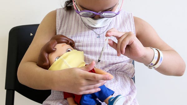 Helena Oliveira dos Santos vaccinates her doll  af