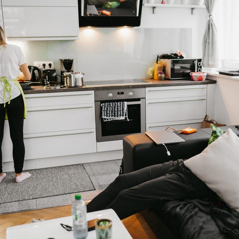 Young woman preparing food in kitchen while man sl