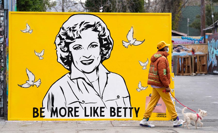 A man walks a dog past a new mural of the late actress Betty White by artist Corie Mattie, Tuesday, Jan. 13, 2022, in Los Angeles.