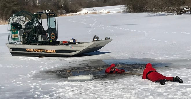 Forest Rangers Mike Burkholder, in water, and Jeremy Oldroyd demonstrate an ice rescue Jan. 22 at the annual Winter Living Celebration at Rogers Environmental Education Center in Sherburne.