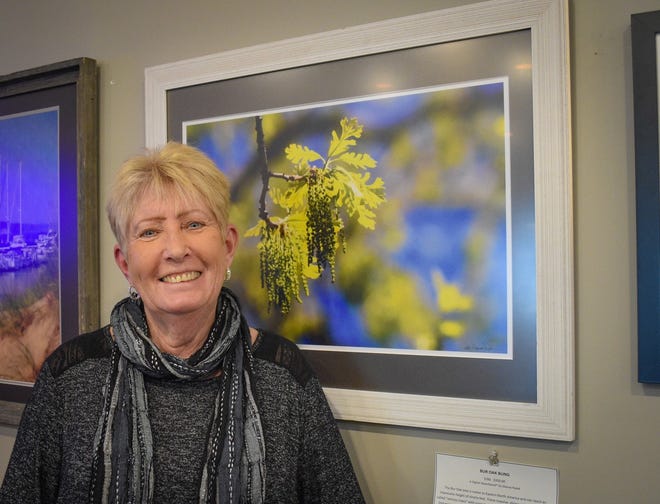Photographer Dianne Rozak’s photos are sometimes mistaken for paintings because of the unique editing technique she created using components of three software programs. Here, she stands with her photo, “Bur Oak Bling,” at R Coffee Corner in Port Clinton. The shop sells several of Rozak’s photos.