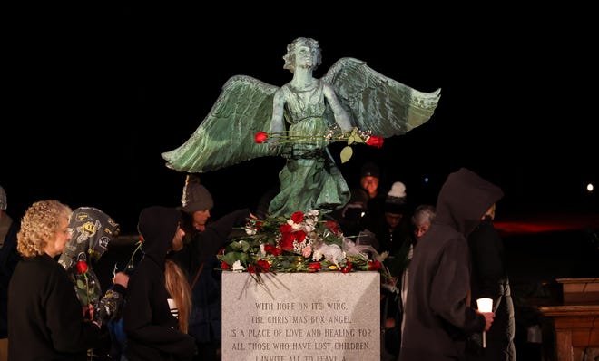 Attendees of a previous Stow Christmas Box Angel of Hope Memorial’s annual candle lighting ceremony lay flowers at the feet of the angel in remembrance of children that died too soon. The memorial is located in Silver Springs Cemetery in Stow. This year's candle lighting ceremony will be Dec. 11.