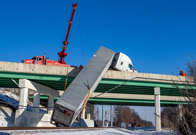 A FedEx semi comes to rest over train tracks after its trailer toppled over an Indiana Toll Road bridge on Interstate 80/90, at Currant Road, on Wednesday, Jan. 26, 2021, in Mishawaka. Near zero temperatures and icy roads caused multiple accidents in the area on Wednesday morning.