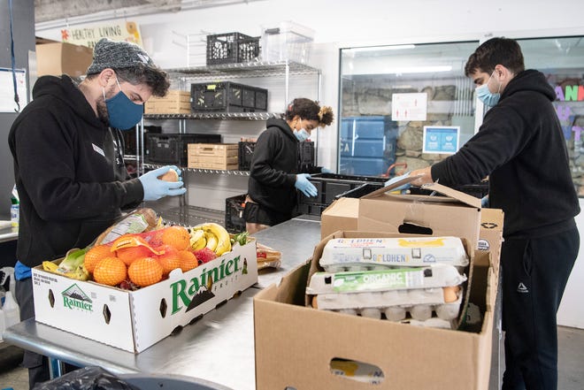 From left, Miguel Hernandez, Tiphereth Hassan and Kyle Patterson sort through donated produce at YMCA in Asheville January 25, 2022.